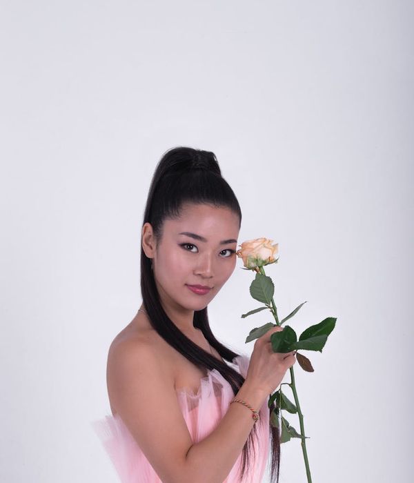 Woman in a dynamic, graceful pose against a dark background with cyan light trails.